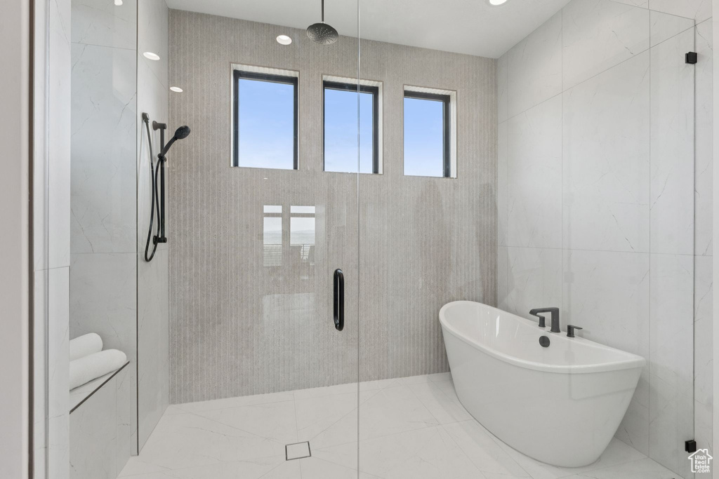 Bathroom featuring a stall shower, a freestanding tub, and tile walls