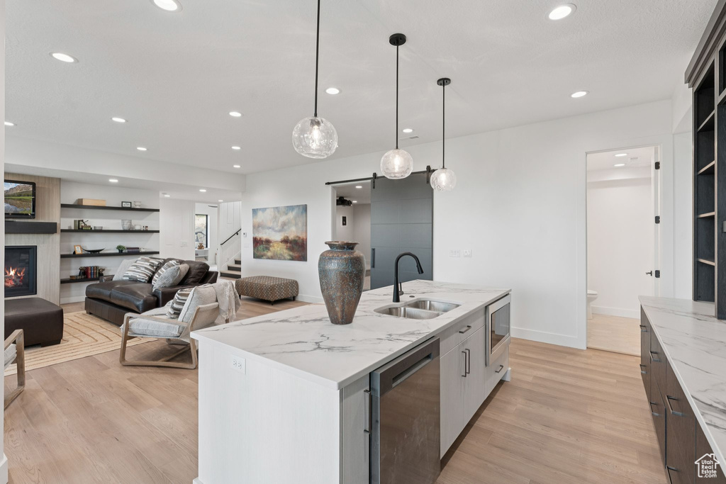 Kitchen with appliances with stainless steel finishes, light wood finished floors, recessed lighting, a center island with sink, and pendant lighting