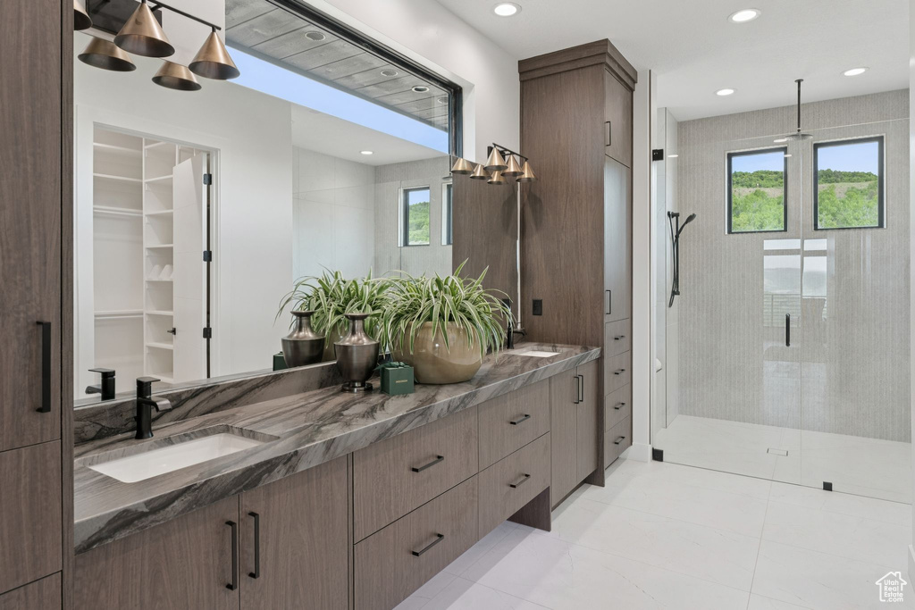 Bathroom featuring plenty of natural light, a shower stall, double vanity, tile patterned floors, and recessed lighting