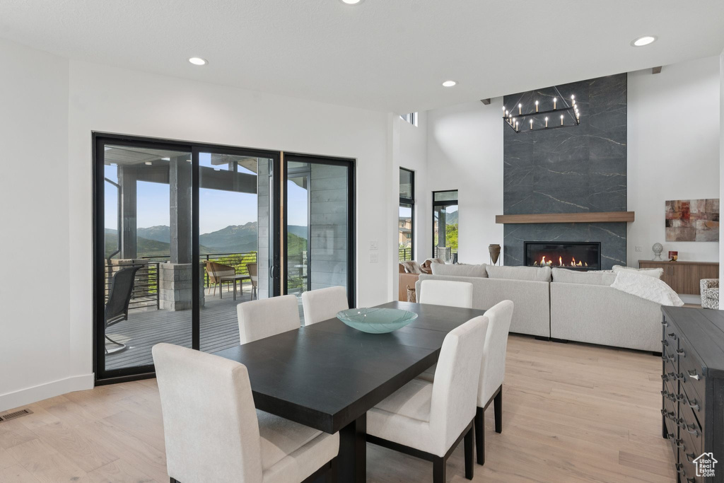 Dining area with light wood finished floors, recessed lighting, a chandelier, a high end fireplace, and a mountain view