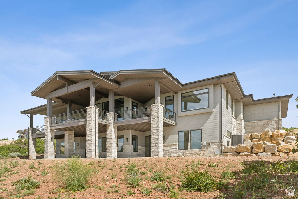 Rear view of house featuring a balcony and stone siding