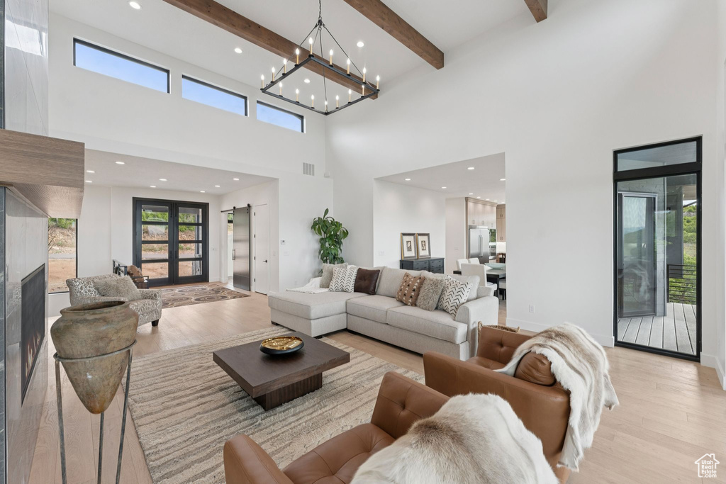 Living room with light wood-style flooring, a high ceiling, plenty of natural light, beam ceiling, and recessed lighting