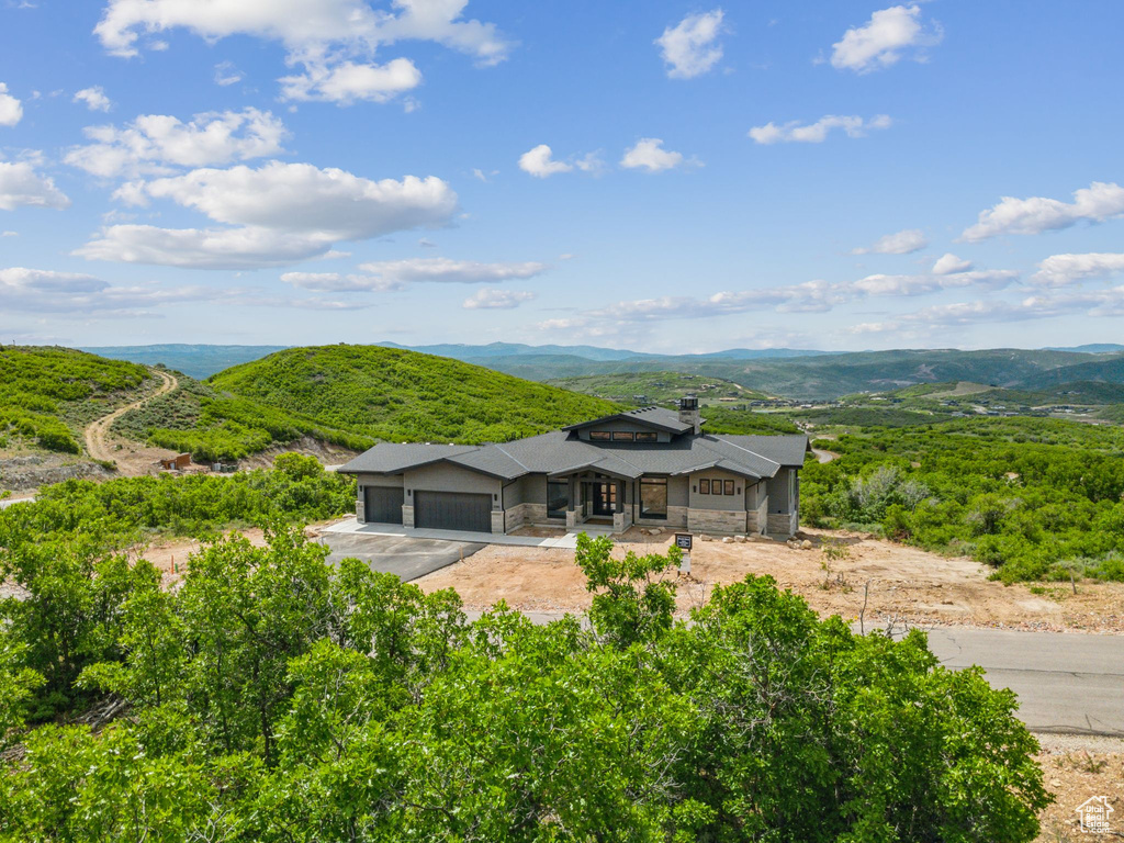 View of front facade featuring a garage, stone siding, asphalt driveway, and a mountain view