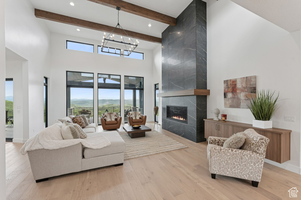 Living area with a high ceiling, wood finished floors, a high end fireplace, plenty of natural light, and beam ceiling