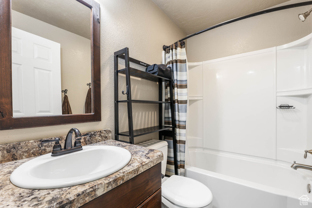 Bathroom featuring vanity, shower / tub combo, and a textured wall