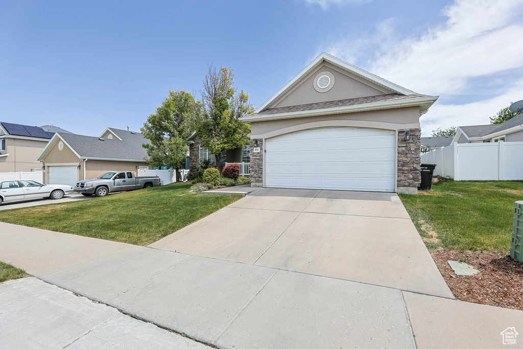 View of front of home with stone siding, concrete driveway, an attached garage, and stucco siding