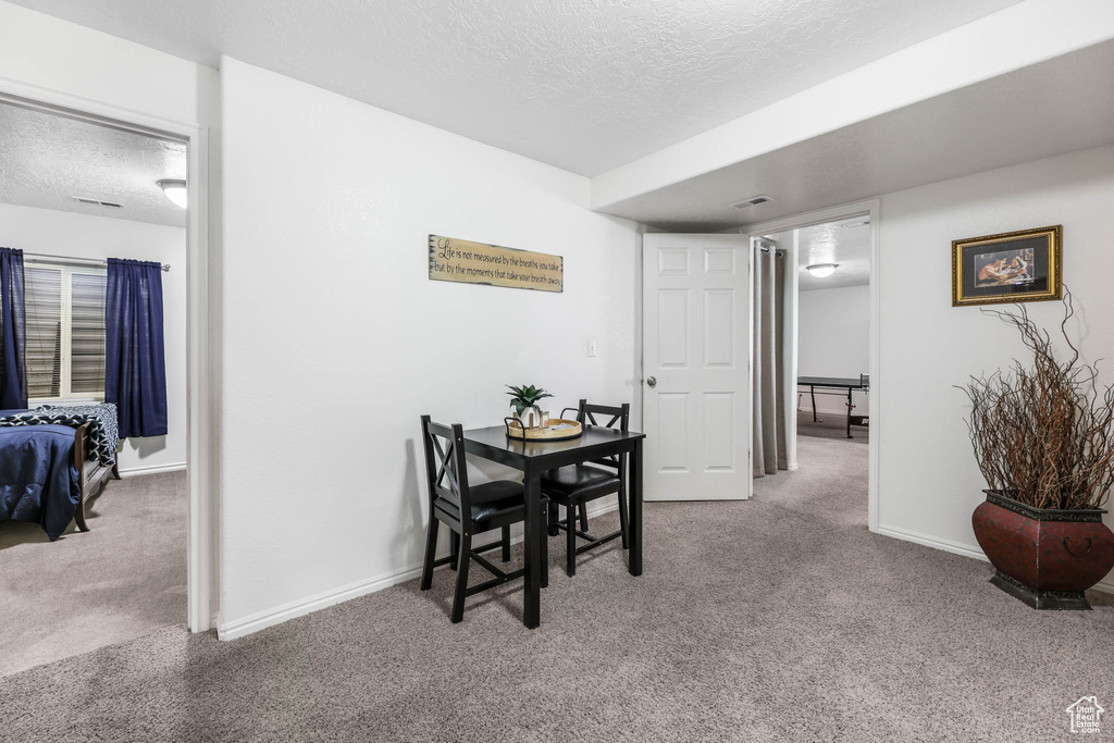 Carpeted dining area with a textured ceiling and baseboards