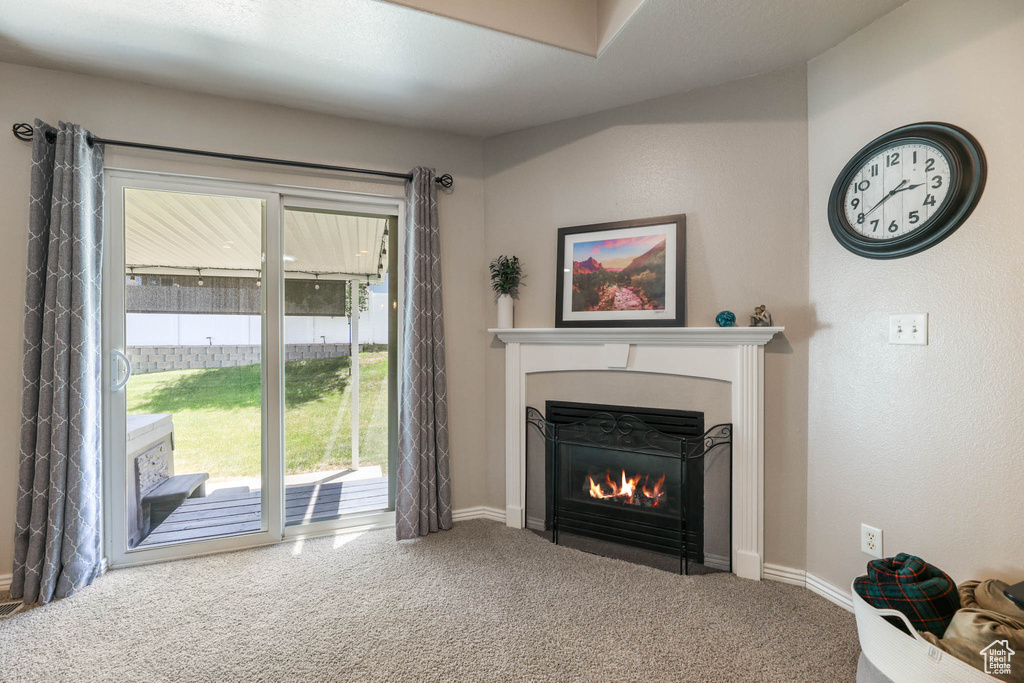 Living area with a fireplace with flush hearth and carpet floors