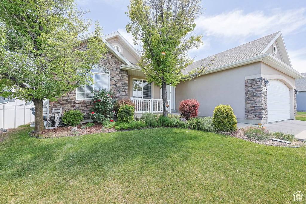 View of front of property featuring stone siding, a front yard, and an attached garage