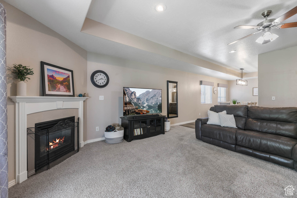 Living area featuring carpet floors, a glass covered fireplace, and ceiling fan