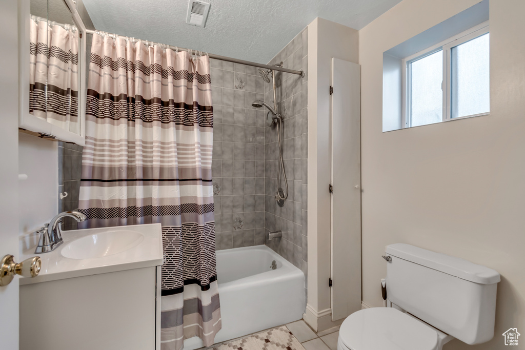 Bathroom featuring shower / bathtub combination with curtain, vanity, tile patterned flooring, and a textured ceiling