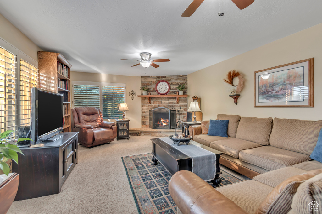 Carpeted living room featuring ceiling fan and a fireplace