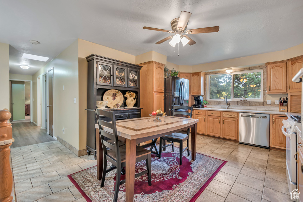 Kitchen with stainless steel dishwasher, refrigerator with ice dispenser, light countertops, a ceiling fan, and gas range gas stove