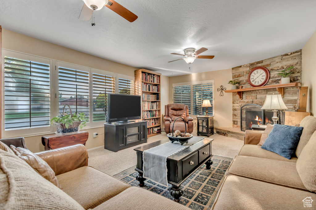 Carpeted living room featuring a ceiling fan and a fireplace