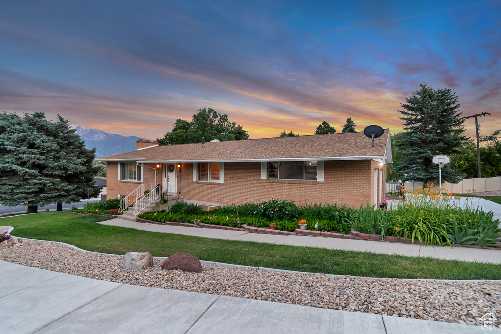 Ranch-style home featuring brick siding, a yard, a chimney, and a mountain view