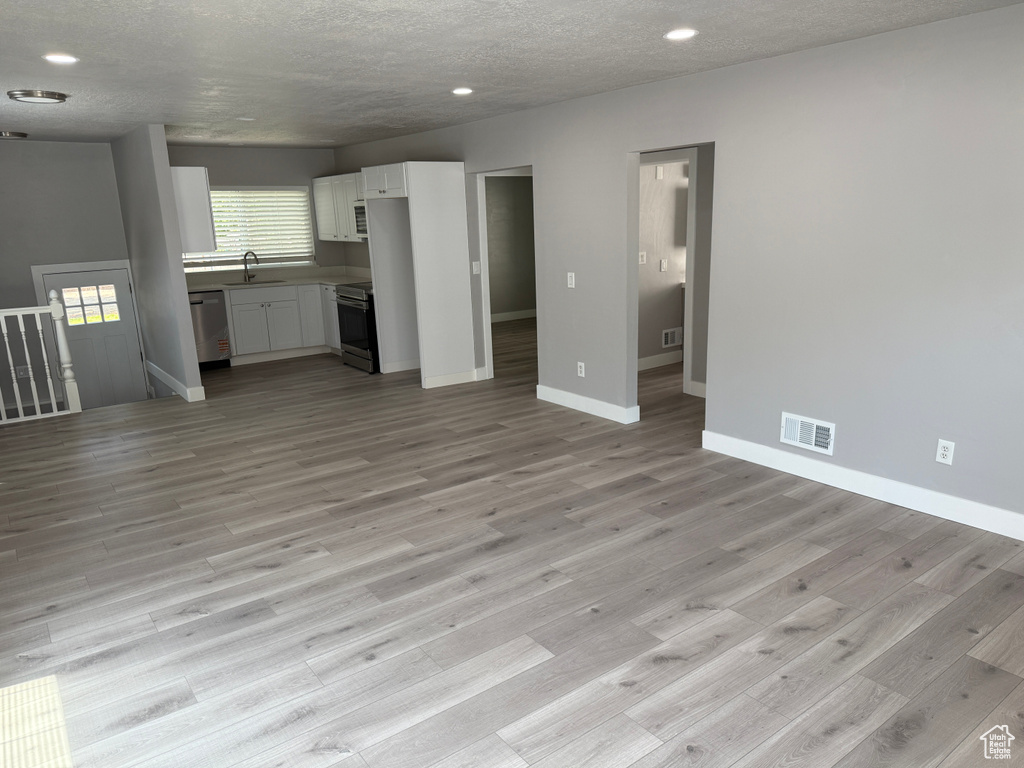 Unfurnished living room featuring light wood finished floors, recessed lighting, and a textured ceiling