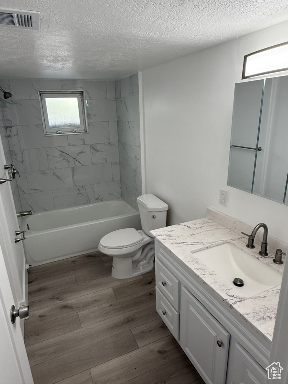 Bathroom with vanity, a textured ceiling, shower / tub combination, and wood finished floors