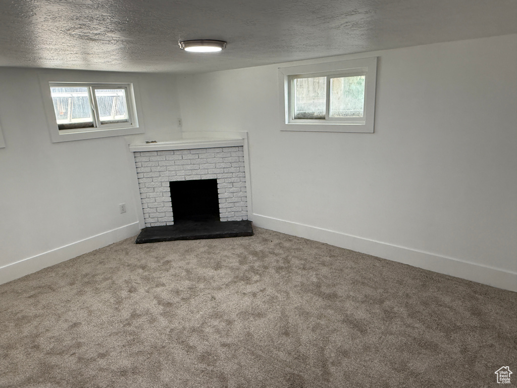 Unfurnished living room with a textured ceiling, a brick fireplace, and carpet