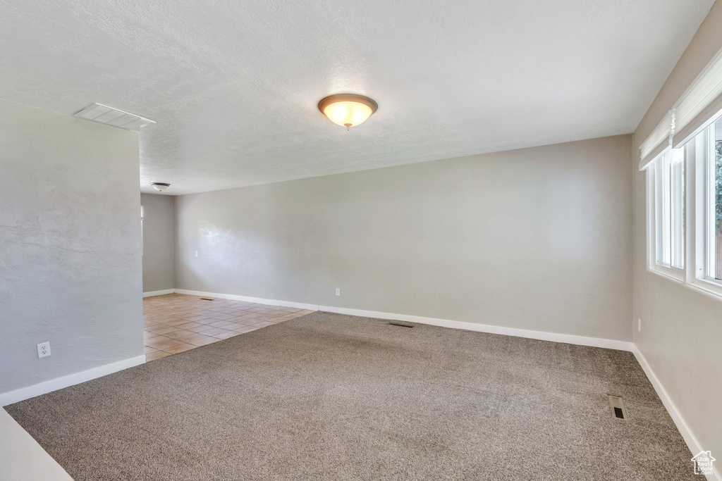 Carpeted empty room with baseboards and tile patterned floors
