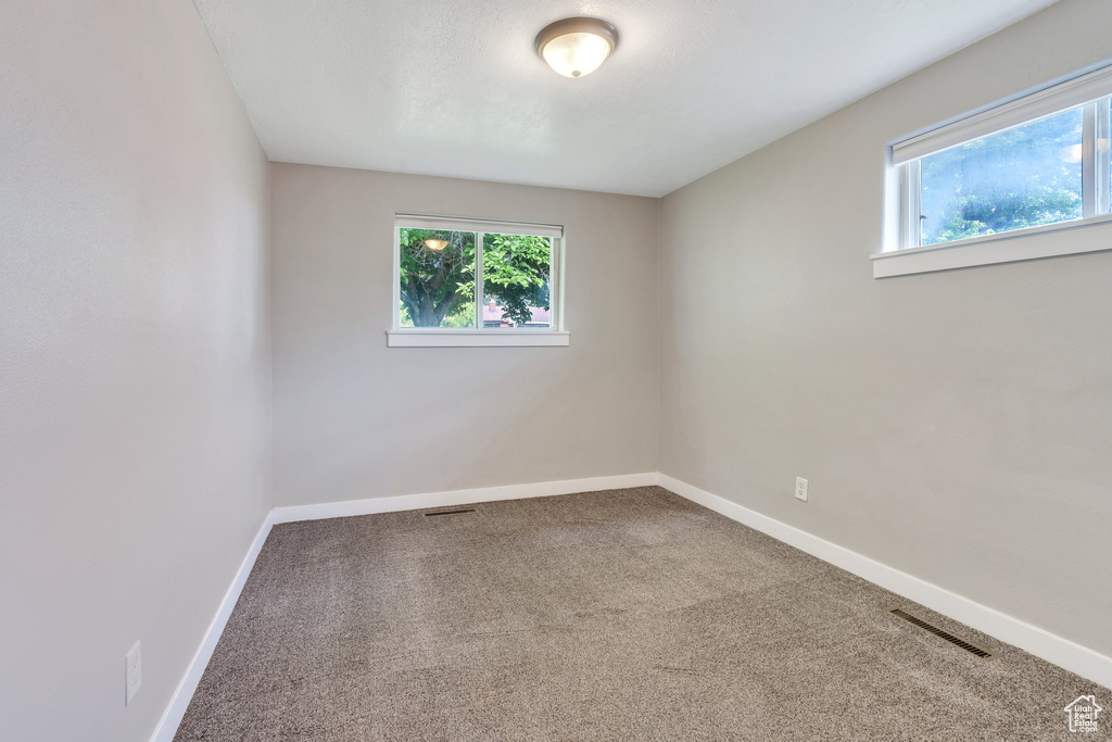 Empty room featuring healthy amount of natural light and carpet