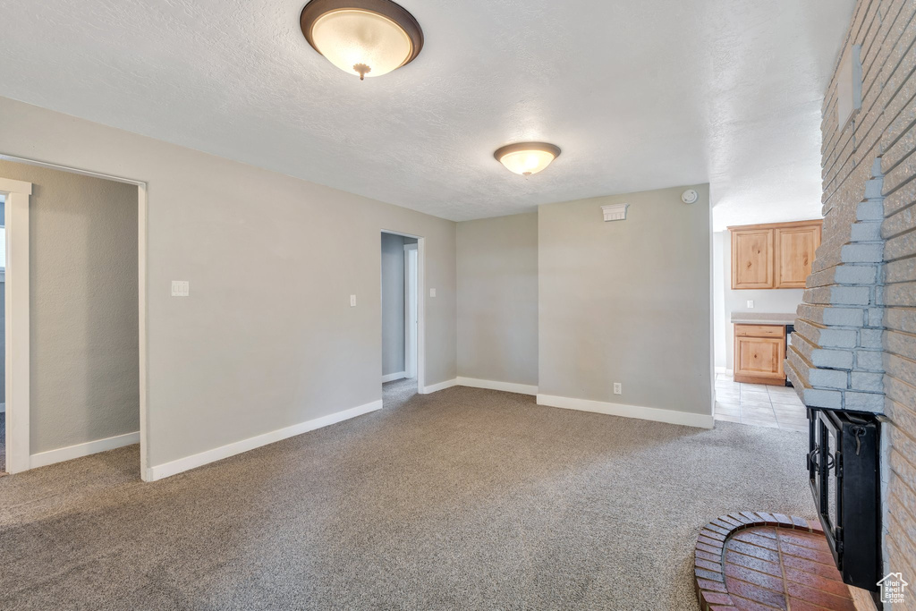 Unfurnished living room featuring light colored carpet and a textured ceiling