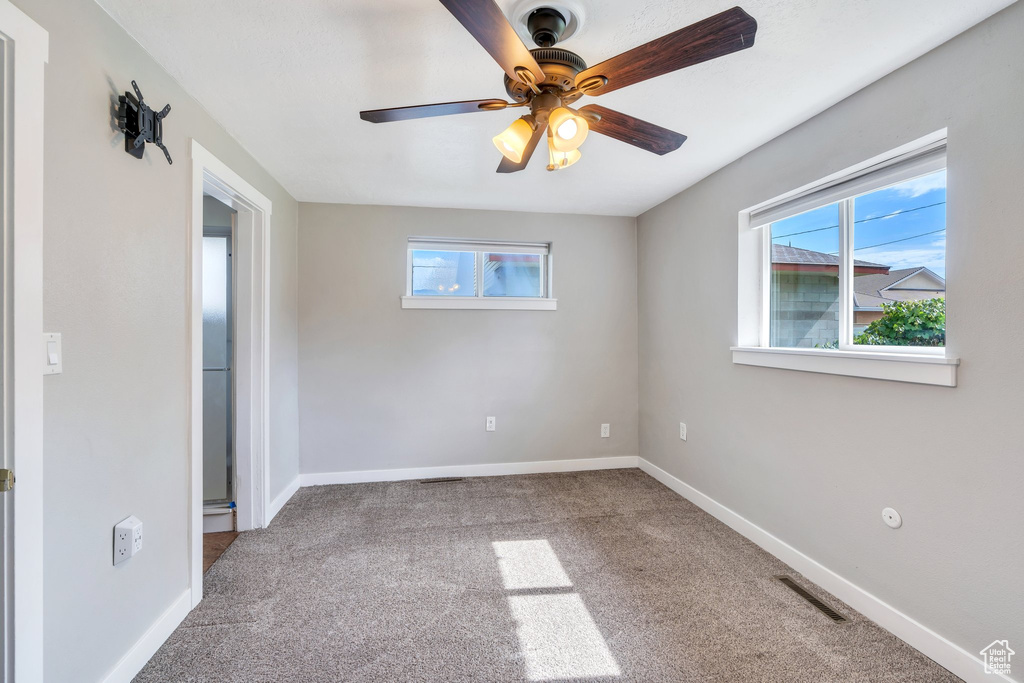 Unfurnished room with carpet floors, healthy amount of natural light, and a ceiling fan