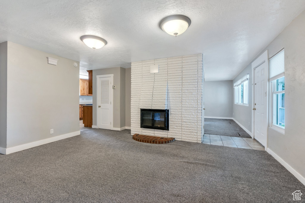 Unfurnished living room with carpet floors, a textured ceiling, and a fireplace