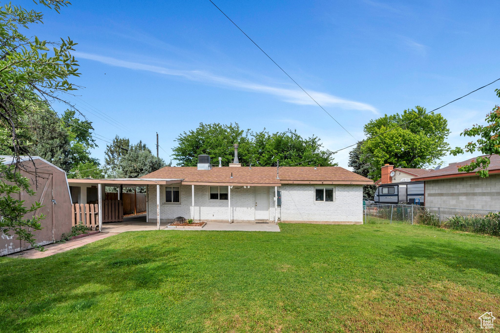 Rear view of property featuring a patio area, brick siding, a storage shed, and a chimney