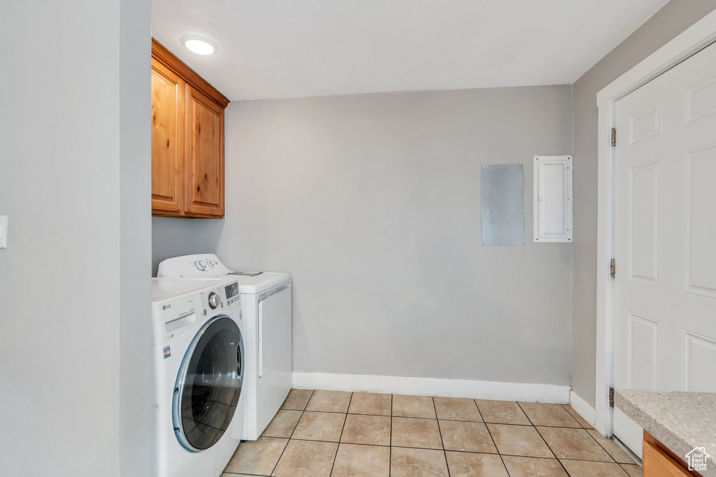 Washroom featuring cabinet space, washing machine and clothes dryer, and light tile patterned floors