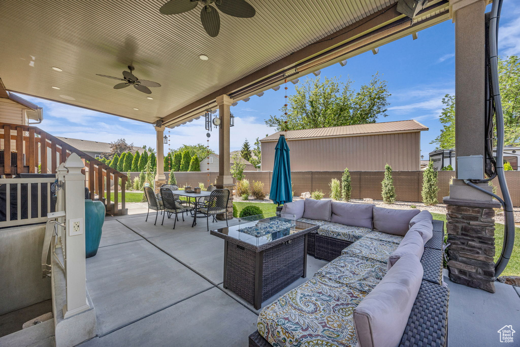 Fenced backyard featuring an outdoor living space with a fire pit, outdoor dining space, a ceiling fan, and a patio area