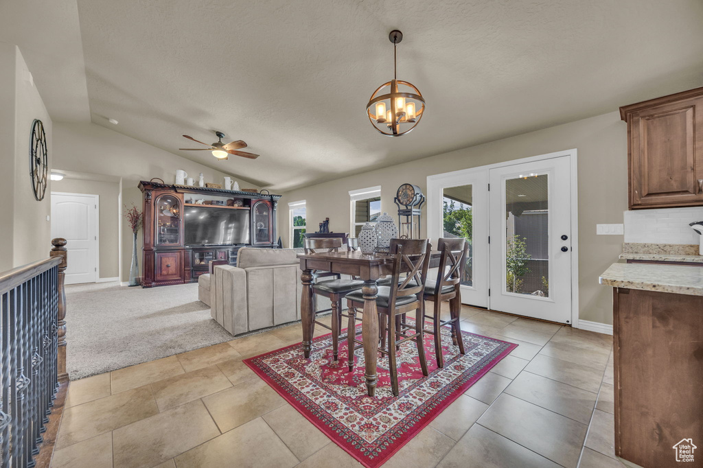 Dining area featuring a chandelier, a ceiling fan, lofted ceiling, a textured ceiling, and light tile patterned floors