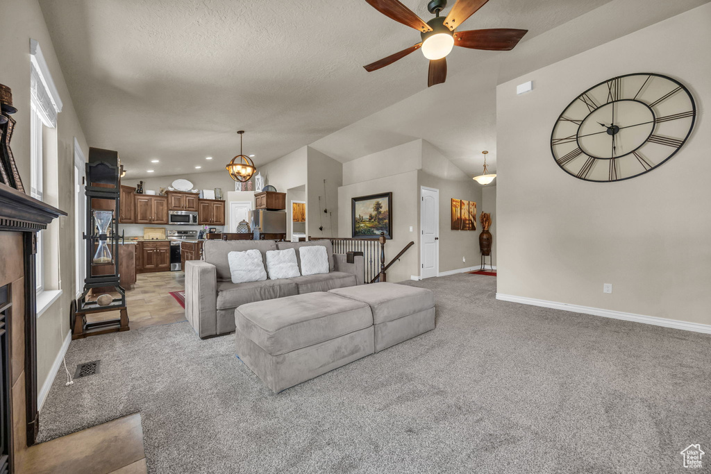 Living area featuring light carpet, a ceiling fan, vaulted ceiling, a chandelier, and recessed lighting