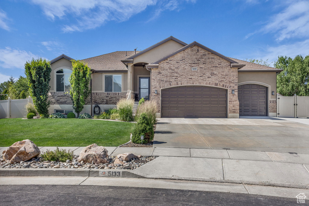 View of front of property featuring stucco siding, an attached garage, driveway, and a gate