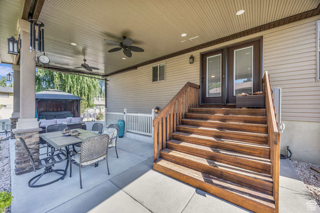 View of patio with outdoor dining area, ceiling fan, and a gazebo