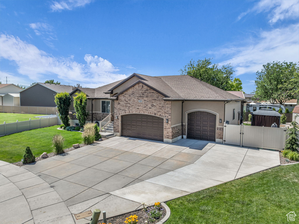 View of front of home with a garage, a gate, driveway, stucco siding, and roof with shingles