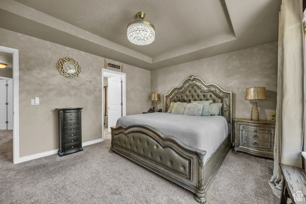 Carpeted bedroom with baseboards and a tray ceiling