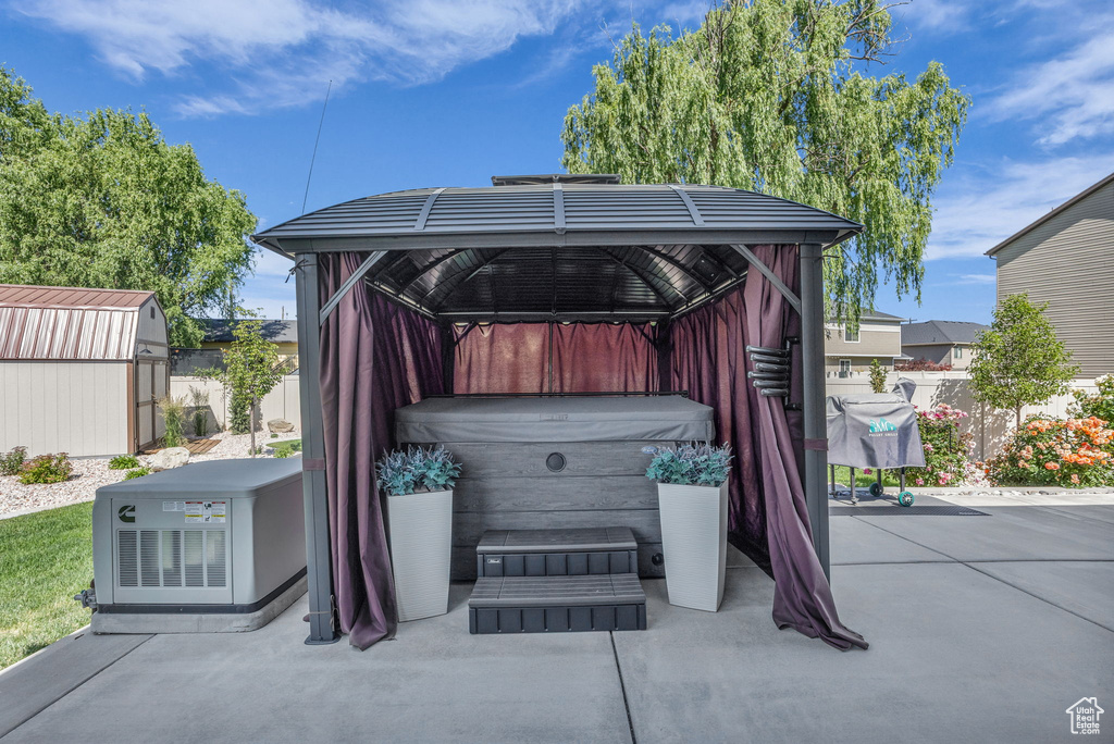 View of patio / terrace with a hot tub, a storage unit, and a gazebo