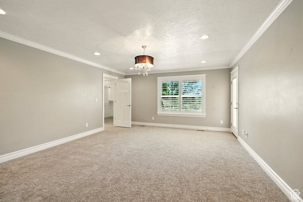 Empty room featuring crown molding, a textured ceiling, a chandelier, recessed lighting, and light carpet