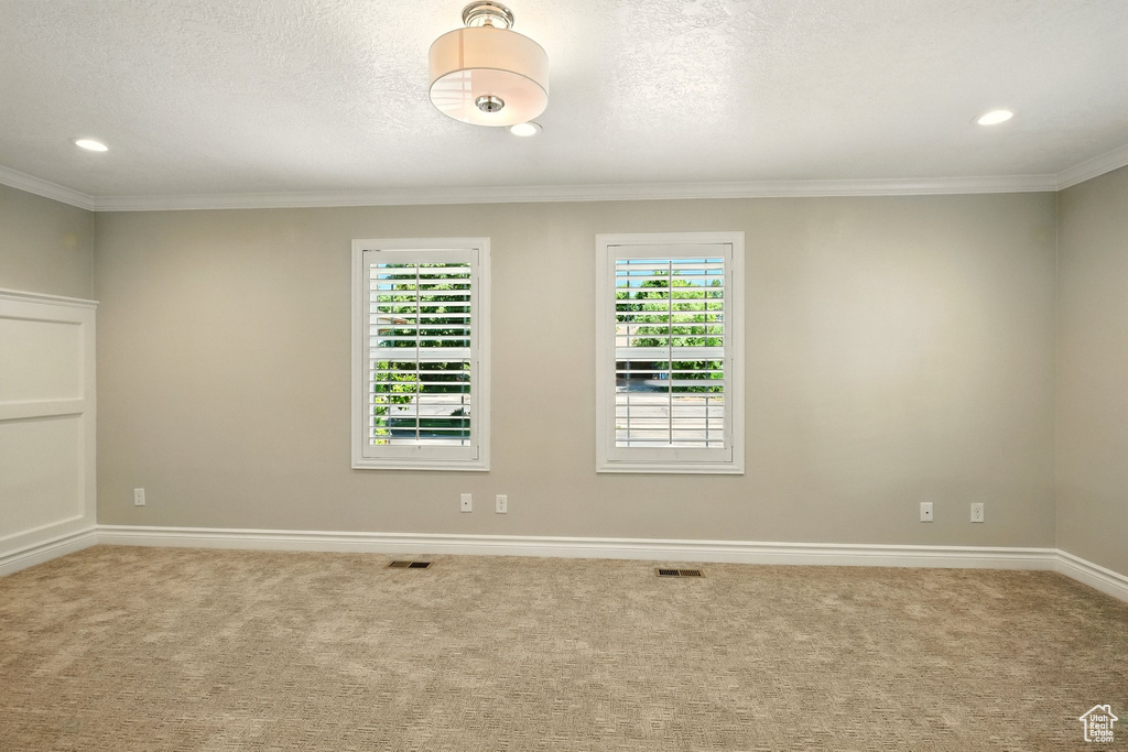 Empty room with carpet, crown molding, recessed lighting, and a textured ceiling