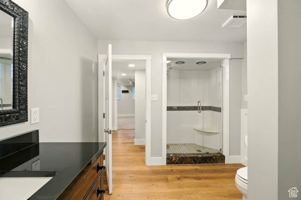 Full bath with a stall shower, wood finished floors, vanity, and recessed lighting