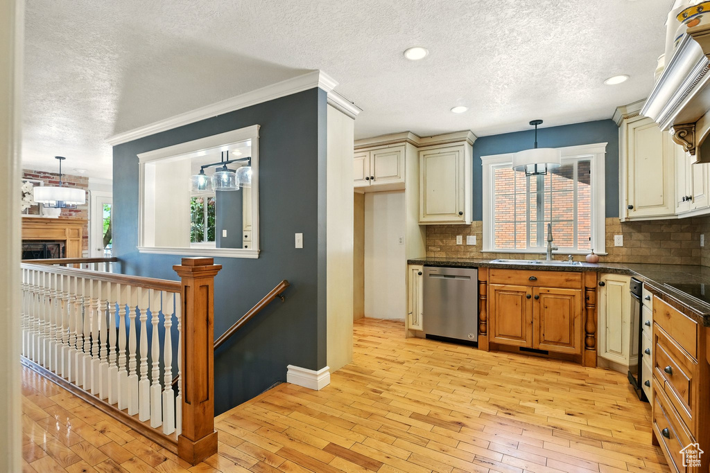 Kitchen with stainless steel dishwasher, a textured ceiling, dark countertops, decorative backsplash, and cream cabinets