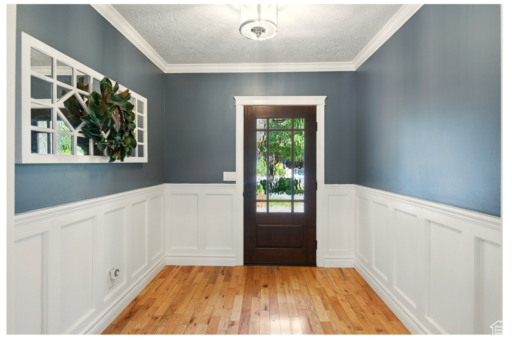 Foyer entrance featuring a textured ceiling, wainscoting, and light wood-type flooring