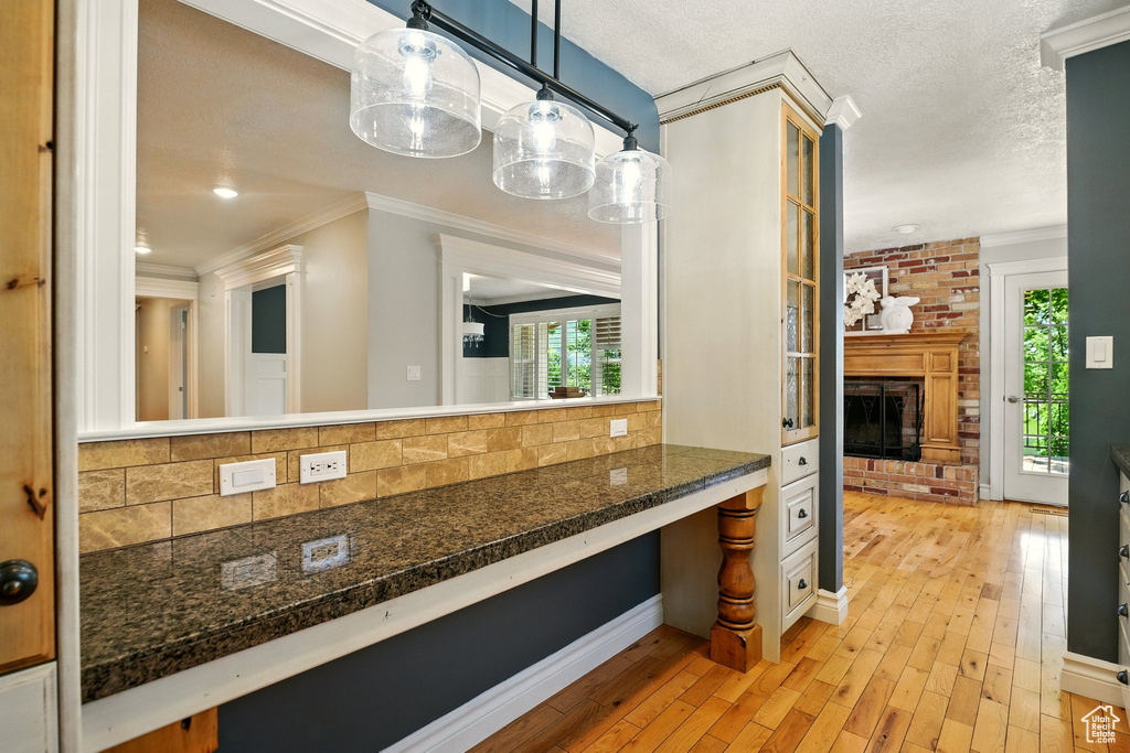 Bathroom with ornamental molding, decorative backsplash, wood-type flooring, a brick fireplace, and a textured ceiling
