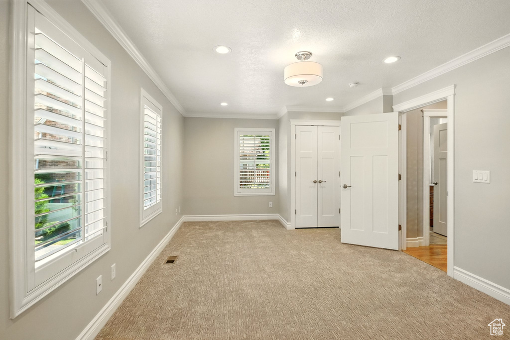 Unfurnished bedroom with light colored carpet, recessed lighting, crown molding, and a closet