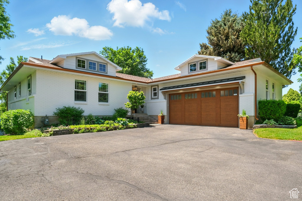 View of front facade with brick siding, asphalt driveway, and a garage