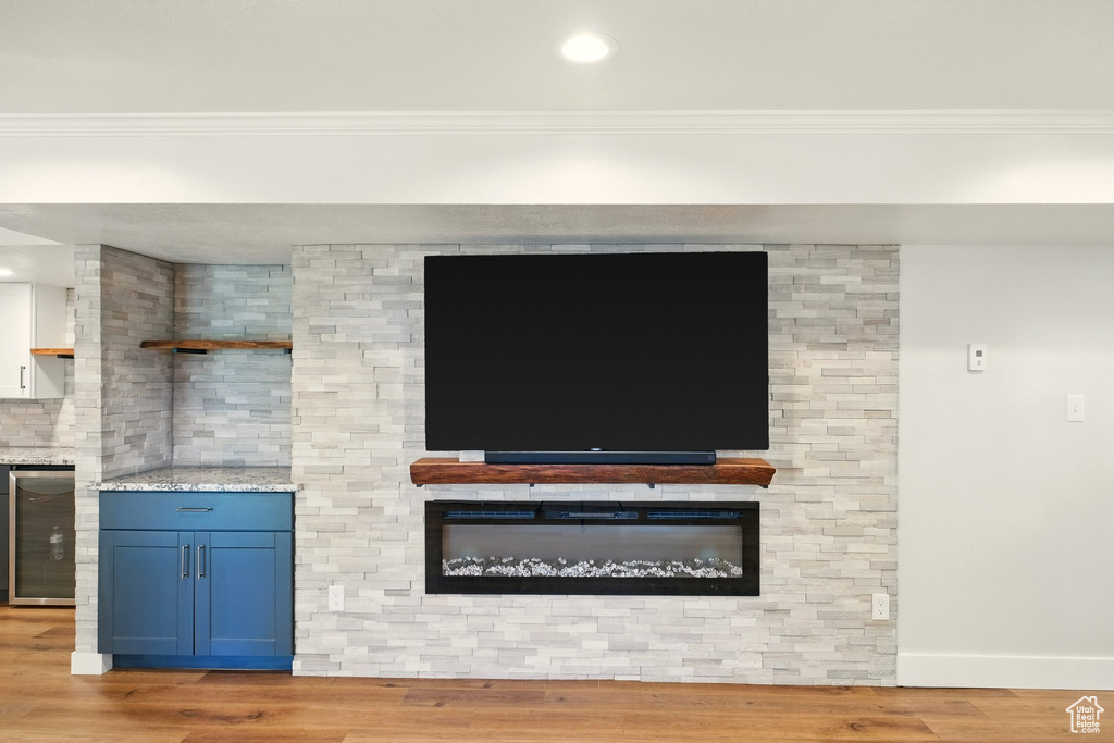 Detailed view of wine cooler, crown molding, and wood finished floors