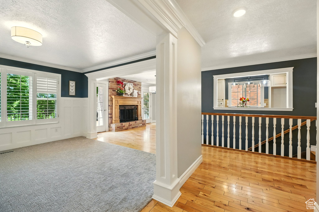 Hallway with a textured ceiling, plenty of natural light, crown molding, a wainscoted wall, and hardwood / wood-style flooring