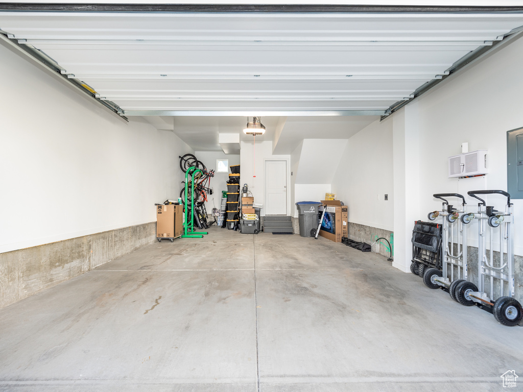 Garage featuring a garage door opener and a wall unit AC