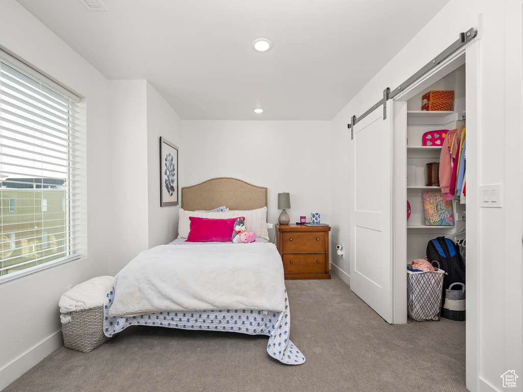 Carpeted bedroom with a barn door, multiple windows, and recessed lighting