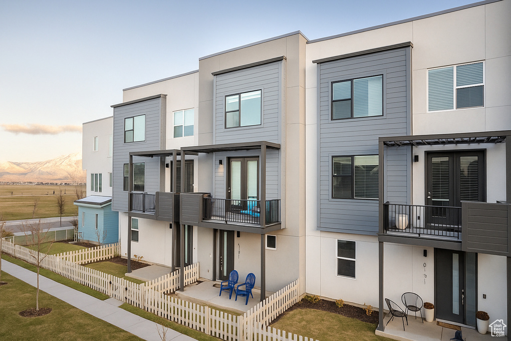 Rear view of property with a balcony, stucco siding, and a mountain view